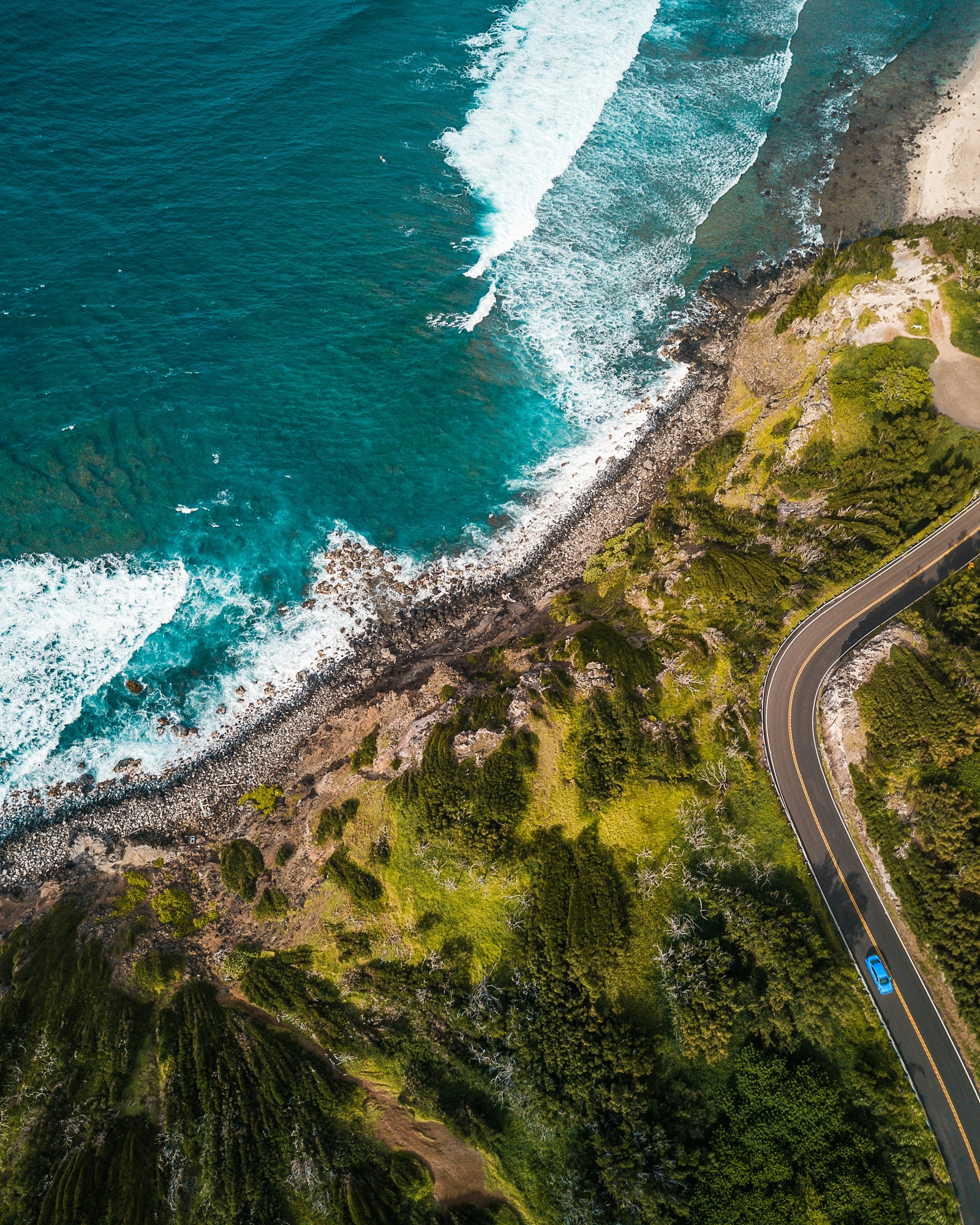 A winding coastal road between green hills and turquoise water
